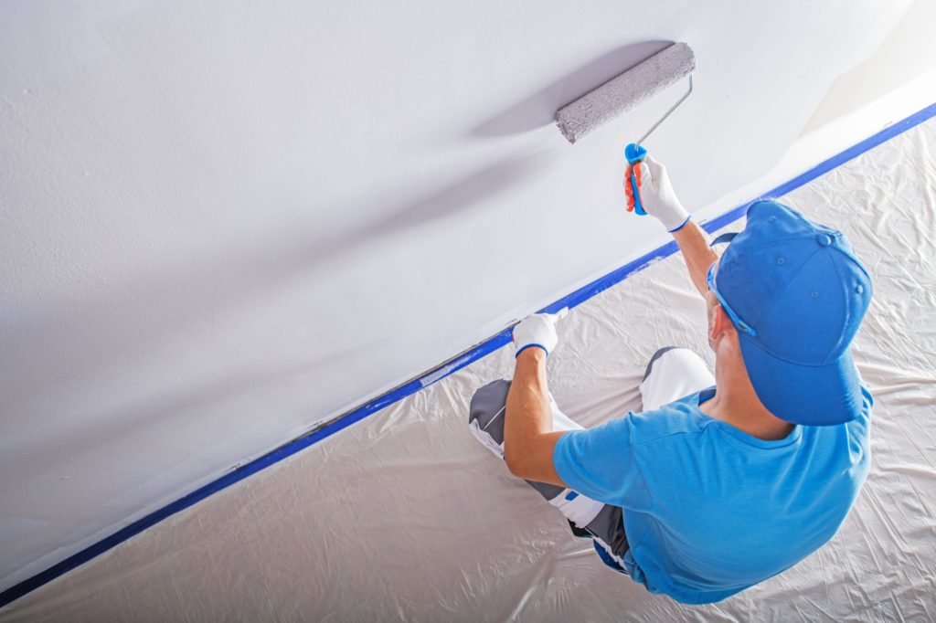 a man in a white coat fixing a ceiling